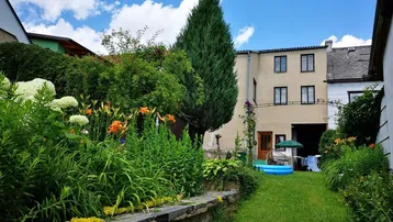 Gepflegter Gartenbereich mit Rasenfläche, Blumenbeeten und einem kleinen Pool vor dem Haus.
