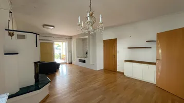 Geräumiges Wohnzimmer mit Parkettboden, Kronleuchter und einem traditionellen Kachelofen.