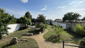 Großer, terrassierter Garten mit gepflasterten Wegen, Rasenflächen und verschiedenen Pflanzen.