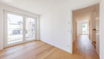 Helles Zimmer mit Holzboden und französischem Balkon, bietet Blick auf die Umgebung.
