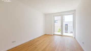 Helles Zimmer mit Holzboden und französischem Balkon, ideal als Schlaf- oder Gästezimmer.