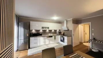 Moderne Einbauküche mit weißen Fronten, Edelstahlgeräten und Holzboden.