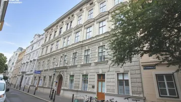 Klassisches Altbaugebäude mit traditioneller Fassade an einer Stadtstraße, umgeben von weiteren historischen Bauten.