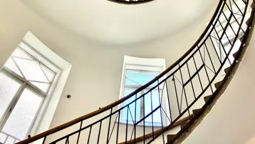Elegantes Treppenhaus mit geschwungener Wendeltreppe und schmiedeeisernem Geländer in einem Altbau.