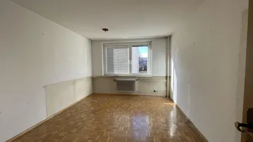 Geräumiges Schlafzimmer mit Parkettboden und viel Tageslicht.