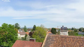Blick über die Dächer der umliegenden Häuser und die grüne Landschaft mit Fernsicht.