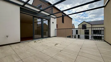 Große geflieste Terrasse mit Metallgeländer und Blick auf die umliegenden Gebäude.