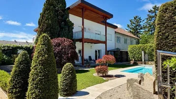 Großzügiger Gartenbereich mit Pool, gepflegter Rasenfläche und schöner Bepflanzung hinter dem Haus.