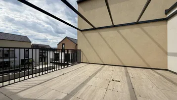 Geräumige Dachterrasse mit Fliesenboden und schwarzem Metallgeländer, ideal für Entspannung im Freien.