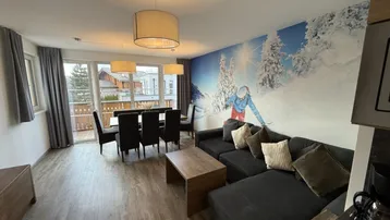 Helles Wohn- und Esszimmer mit großem Wandbild, Balkonzugang und modernem Interieur.