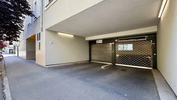 Eingangsbereich einer Tiefgarage mit Rolltoren und Zufahrt von der Straße.