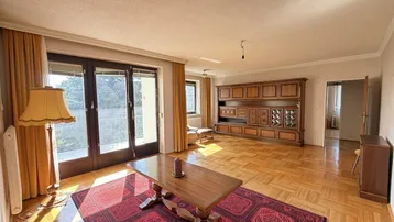 Geräumiges Wohnzimmer mit Parkettboden, großem Holzschrank und Zugang zu einem Balkon oder einer Terrasse.