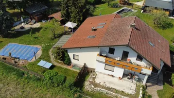 Luftaufnahme eines Einfamilienhauses mit großem Garten, Pool und Terrasse in ländlicher Umgebung.