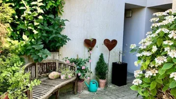 Gemütliche Terrasse mit Holzsitzbank und Pflanzen, ideal zum Entspannen im Freien.