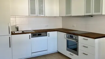 Moderne Einbauküche mit weißen Schränken, Holz-Arbeitsplatten und integrierten Geräten.