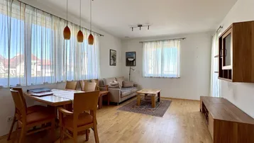 Geräumiger Wohn- und Essbereich mit Holzfußboden und großen Fenstern, hell und einladend.