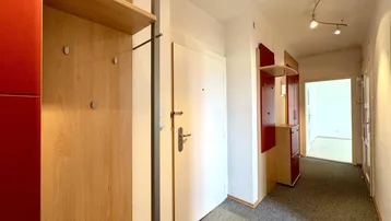 Heller Flur mit Garderobe und Holzmöbeln, der zu weiteren Räumen führt.