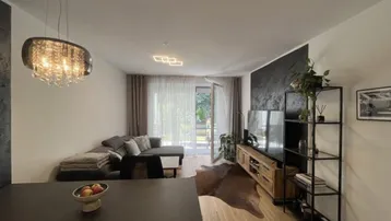 Modernes Wohn-Esszimmer mit Holzboden, dunkler Akzentwand und Zugang zur Terrasse mit Gartenblick.