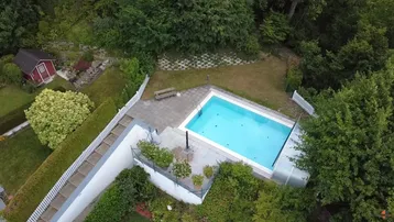 Großer Außenbereich mit privatem Pool, umgeben von viel Grün und Bäumen.