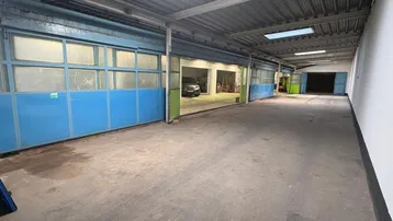 Geräumige Lagerhalle mit mehreren Rolltoren, Oberlichtern und Betonboden, ideal für gewerbliche Nutzung.
