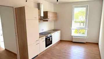 Moderne Küchenzeile mit hellen Schränken, integrierten Geräten und einem Fenster.