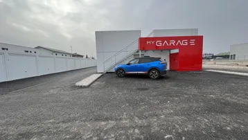 Modernes Garagengebäude mit weißer und roter Fassade sowie einem Außenparkplatz.