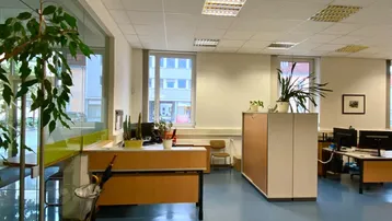Großes, helles Büro mit blauen Bodenfliesen, modernen Möbeln und Blick auf die Straße.