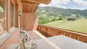 Geräumiger Balkon mit Holzbalken und atemberaubendem Blick auf die umliegende Berglandschaft.