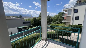 Balkon mit Fliesenboden und grüner Brüstung, bietet weiten Blick auf die Stadt und Berge.