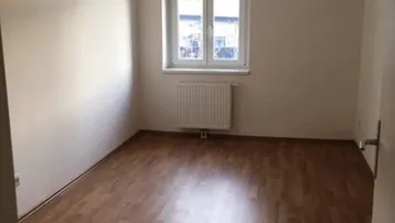 Helles Zimmer mit Laminatboden und Fenster, ideal als Schlaf- oder Arbeitszimmer nutzbar.