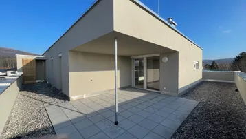 Geräumige Dachterrasse mit modernem Design, Kiesflächen und Bergblick unter blauem Himmel.