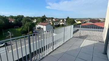 Geräumige Terrasse mit Fliesenboden und Blick auf die Umgebung und die Straße.