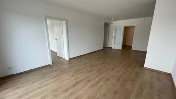 Heller, leerer Wohnbereich mit modernem Laminatboden und weißen Wänden.