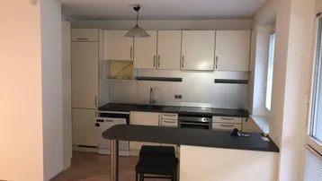 Funktionale Einbauküche mit hellen Schränken, Frühstücksbar und integrierten Geräten.