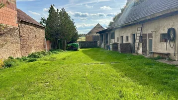 Weitläufiger Gartenbereich eines ländlichen Anwesens mit Nebengebäuden und viel Grünfläche.