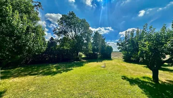 Weitläufiger Garten mit Blick auf die umliegende Landschaft und Felder in der Ferne.