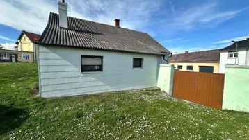 Seitenansicht des Hauses mit einem kleinen Gartenbereich und einer Holztür.
