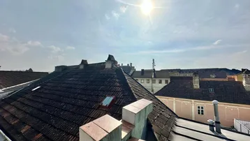Dachlandschaft mit alten Ziegeln und Schornsteinen unter strahlendem Sonnenschein, typisch für die Region.