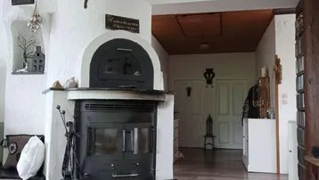 Wohnzimmer mit einem traditionellen Kaminofen und Holzboden, der eine warme Atmosphäre schafft.