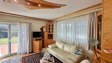 Gemütliches Wohnzimmer mit beiger Couch, Holzelementen und Zugang zum Garten.