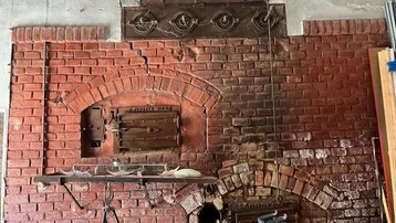 Historischer Backofen oder Kamin aus Ziegeln mit Metalltüren, ein rustikales Element.