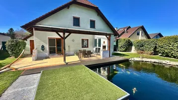 Außenansicht des Hauses mit großem Garten, Teich und sonniger Terrasse.