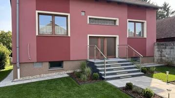 Modernisierte Hausfassade in Rot mit neu angelegtem Vorgarten und Treppenzugang.