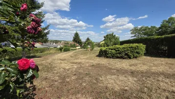 Weitläufiger Garten mit Rasen, Bäumen und Blick auf die ländliche Umgebung.