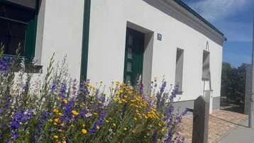 Vorderansicht des Hauses mit blühenden Blumen im Vorgarten unter blauem Himmel.