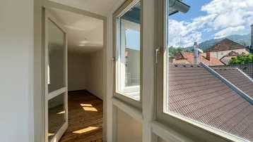 Heller Flur mit Holzboden und Blick auf die Dächer und umliegende Landschaft.