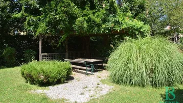 Gemütlicher Sitzbereich im Garten unter einer begrünten Pergola, ideal zum Entspannen im Freien.