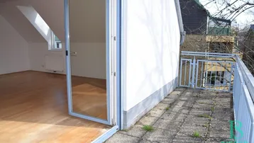 Helles Zimmer mit Holzboden und direktem Zugang zu einer gefliesten Terrasse.