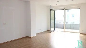 Helles, leeres Zimmer mit Holzboden und großem Balkonzugang, bereit zur individuellen Gestaltung.