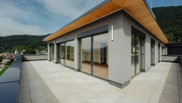 Großzügige Dachterrasse mit Fliesenboden und weitem Blick über die Umgebung und Berge.